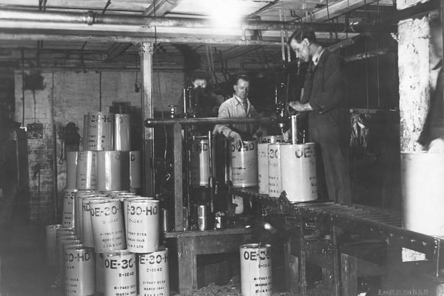 Edward Joy and Sons, filtrate works on Lidacre Street in March 1945. This shows two automotive filling machines working to fill oil drums. The man on the right is using a machine to insert a oil proof inner seal as an additional protection to the cap, for the prevention of oil spillage.
