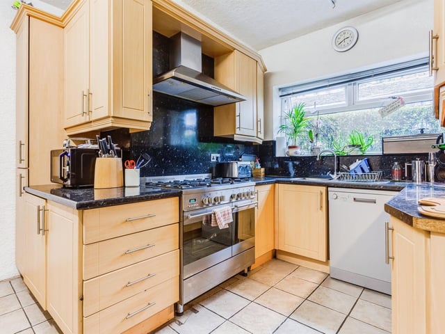 The kitchen has fitted units and a large window.