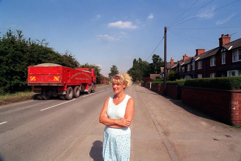 Locals were unhappy with noise and disruption from lorries in July 1999. Pictured is  Madeline Lloyd watching one of the lorries pass her home and other houses on Park Lane.