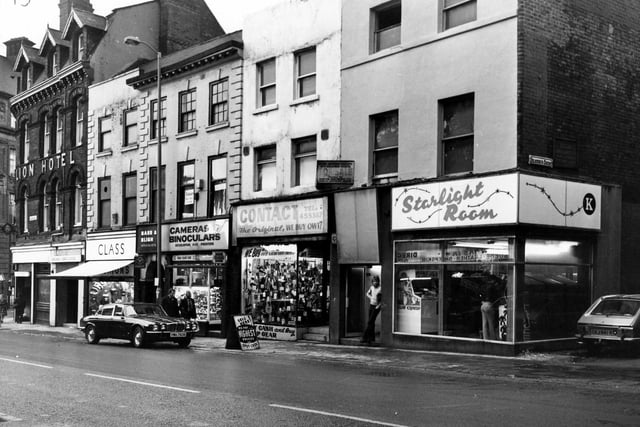 Shops on Lower Briggate in December 1979. On the left is the Golden Lion Hotel by the junction with Swinegate, then is Class menswear, Bass and Bligh, camera and binocular repairs, Contact second hand goods and Starlight Room amusements. On the right is the junction with Heaton's Court.