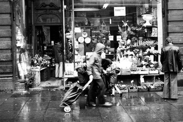 Robinson's Seeds Ltd. (proprietor: William Green) of 13 Market Buildings on the Vicar Lane side of Kirkgate Market. Trays of plants are on display outside the shop with various garden equipment in the shop window. Several people are outside the shop including two children. Pictured in January 1979.