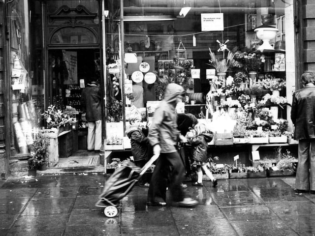 Robinson's Seeds Ltd. (proprietor: William Green) of 13 Market Buildings on the Vicar Lane side of Kirkgate Market. Trays of plants are on display outside the shop with various garden equipment in the shop window. Several people are outside the shop including two children. Pictured in January 1979.