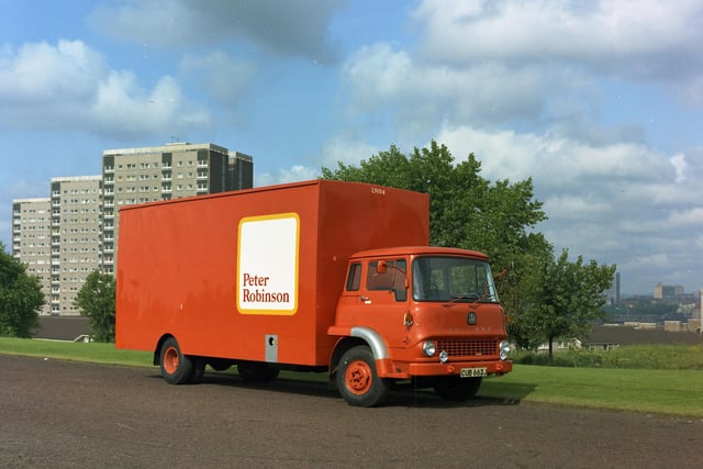 June 1971 and an orange Bedford HGV which belongs to a company called Peter Robinson Transport makes its way through Leeds There are three tower blocks on the left side of this image behind the van. The city skyline is visible to the right.
