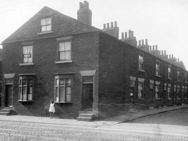 A little girl stands on Low Road outside number 40 which is the property of Samuel Mulholland at 42 lived James Richardson, grinder. View of Latimer Street shows a row of back-to-back terraced houses. A woman stands in doorway of first house.