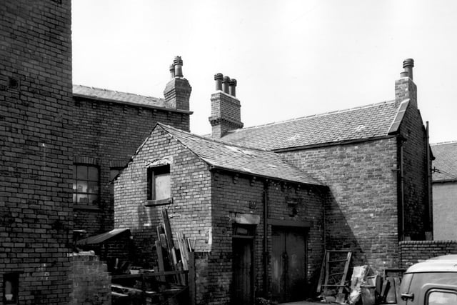 Two one-storey outbuildings on Barnet Street. These buildings are located to the rear of two shops on Tong Road. Number 156 is Clifford Medway, jewellers, and number 158 is Jean Hairstylist. The back of number 2 Strawberry Road can be seen towards the right. Pictured in  June 1965.