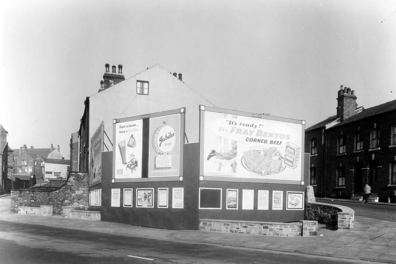 This view is looking from Park Lane to the junction with Hanover Terrace on the left and Hanover Street on the right. A vacant piece of land has been surrounded by advertising hoardings. There are large posters for Kit Kat bars, Jubilee stout and Fray Bentos corned beef. Pictured in September 1959.