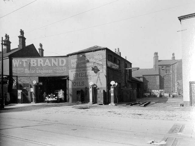A view of W. T. Brand, Motor Engineer on Chapeltown Road, showing garage premises with petrol pumps to rear and side. Visible on the right is the edge of the Cambridge Hotel public house while buildings in the background between the two face onto St. Clement's Place. Pictured in April 1937.
