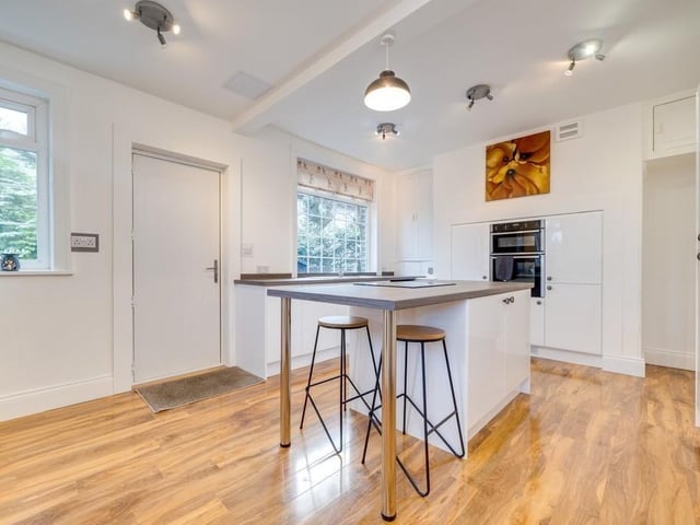 The breakfast kitchen has white gloss units and an island with bar seating.