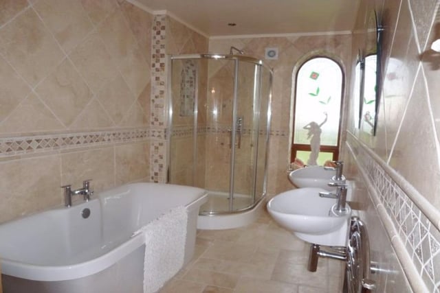 This bathroom has twin wash hand basins, a free standing bath and shower cubicle.