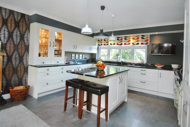 Shaker style units and a central island, with granite worktops, are within the well designed breakfast kitchen.