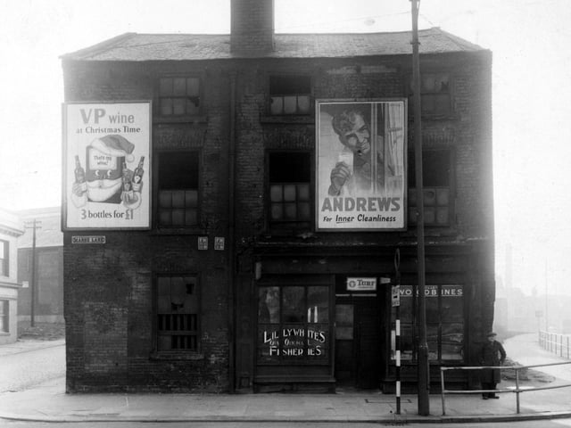 Lillywhites fisheries  on the south east side of Marsh Lane by the junction with Garden Street. Kirkgate East is on the right with iron railings down the side. The upstairs floor of the building is derelict and has billboards outside for VP wine and Andrew's antacid. Advertisements for various tobaccos are in the shop window. An unidentified pub is on the left. An old man and a road sign are outside. Pictured in July 1955.