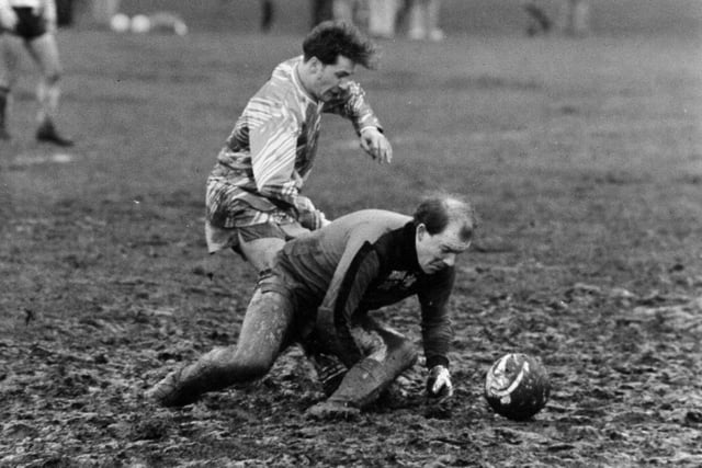 Dirty play. Crown Reserves goalkeeper Craig Eustace scrambles for the ball on a mudbath Stray pitch under pressure from CEGB striker Michael Oakes. Pictured in Febraury 1990.