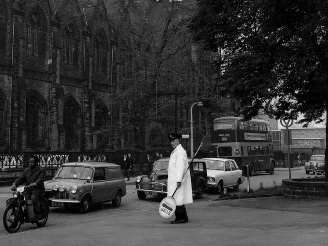 Leeds Grammar School in June 1967. The traffic on the road in front includes a mini van, motor cycle and a bus. A lollipop man is in the foreground.