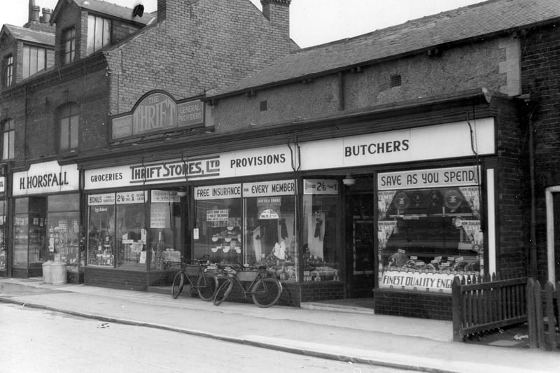 Thrift Stores grocers and butchers departments pictured in April 1937. Delivery bicycles are propped against the shop windows which have displays of goods and advertising. On the left is Hedley Horsfall ironmonger's shop