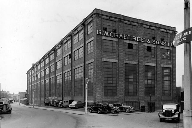 R. W. Crabtree & Sons Ltd factory on Water Lane pictured in March 1954. The iron railings on Water Lane run along Hol Beck which then runs underground towards the front of picture. There are several cars, vans and a lorry parked at side of building.