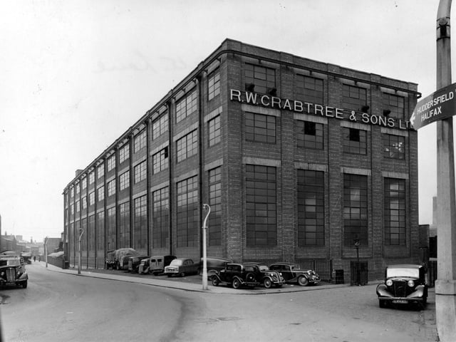 R. W. Crabtree & Sons Ltd factory on Water Lane pictured in March 1954. The iron railings on Water Lane run along Hol Beck which then runs underground towards the front of picture. There are several cars, vans and a lorry parked at side of building.