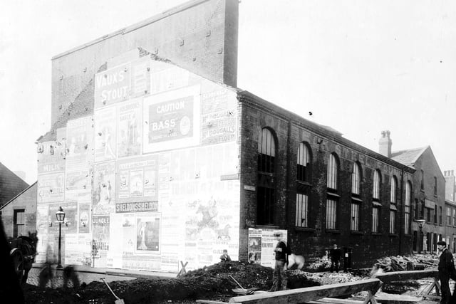 Holbeck Steel foundry looking from junction of David Street with Water Lane. Advertising posters and playbills can be seen to gable end of building. Taken during time of construction work on Water Lane sewer. Pictured in 1906.