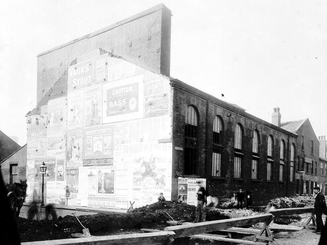 Holbeck Steel foundry looking from junction of David Street with Water Lane. Advertising posters and playbills can be seen to gable end of building. Taken during time of construction work on Water Lane sewer. Pictured in 1906.