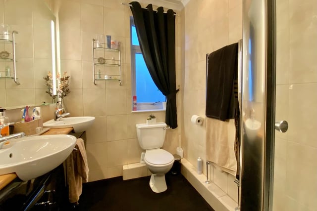 The shower room features his and hers sinks, built in shelving, WC and corner shower.
