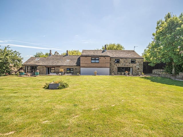 An extensive lawned garden has seating areas and a dedicated barbecue area.