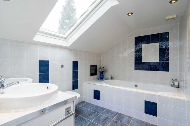 The fully tiled bathroom with twin wash basins and a skylight.