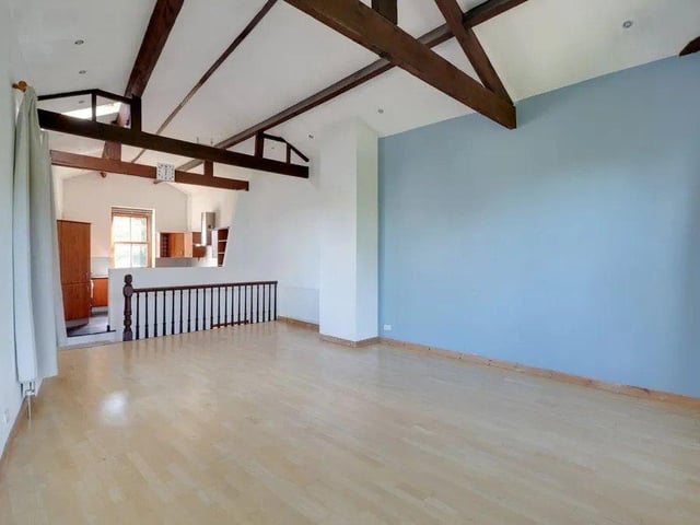 With high apex ceiling featuring exposed timber beams and fabulous picture windows to three aspects, this living room offers an expanse of space ideal for entertaining guests.