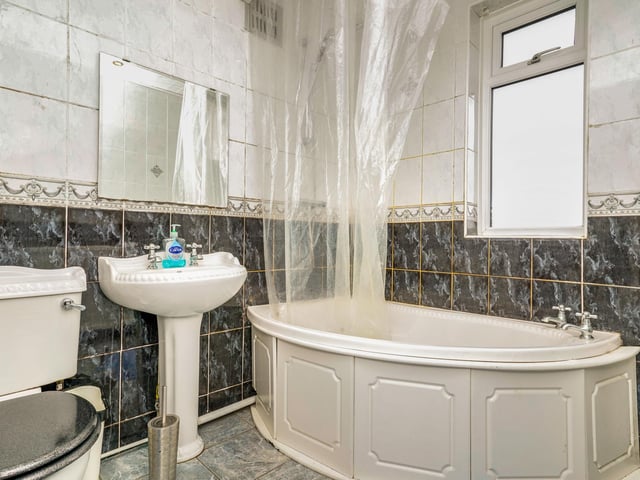 The modern family bathroom comes with a bath and shower unit and gorgeous tiling.