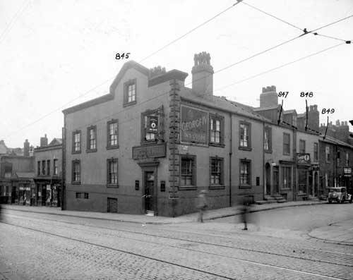 The George IV pub on Woodhouse Lane in September 1935.  To the right is St. James Street, no.3 business of F.J. Cossins and son, artificial limb maker. No.7 which is on the right, Mrs Emily Plowman, fish and chip shop.