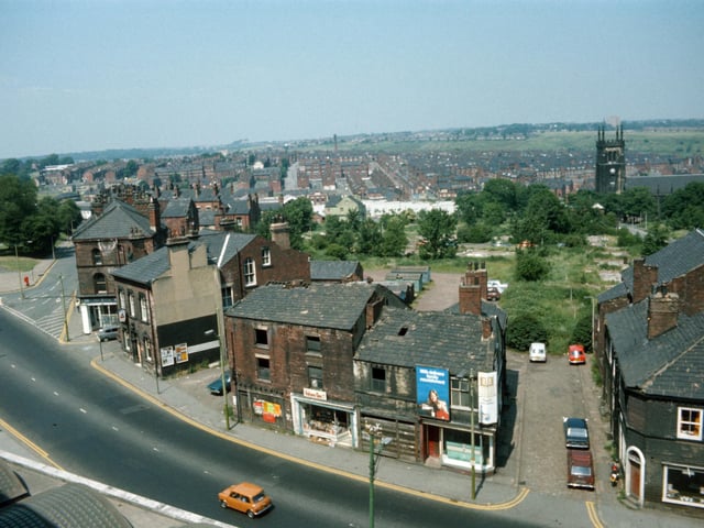 Looking down on Woodhouse taken from Leeds University Engineering Department in June 1975. Woodhouse Lane runs across in the foreground, with Spenceley Street on the right and Raglan Road leading off on the left. Volume One bookshop is seen in the centre in part of a block of derelict buildings due to be demolished. To the left of this is the Pack Horse public house. St. Mark's Church is seen in the background on the right while on the far left is the corner of Woodhouse Moor.