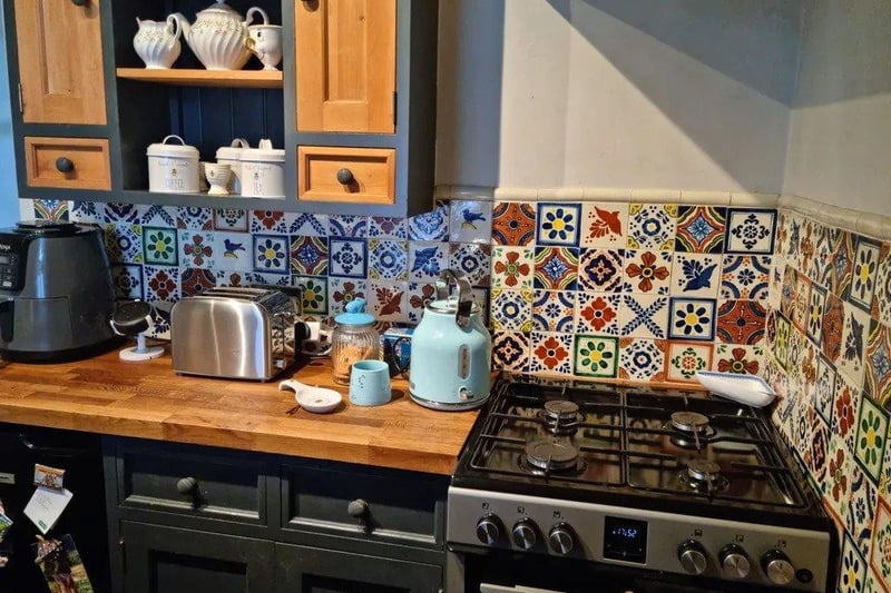 The kitchen is a delightful mix of vintage and contemporary styles, boasting sleek appliances, vibrant tiles and plenty of storage space.