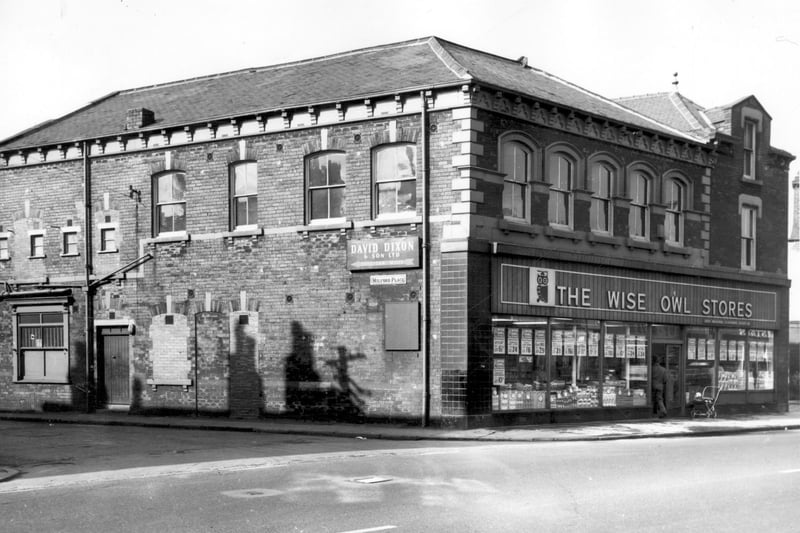 The Wise Owl Stores pictured in March 1966. It was part of Leeds Industrial Co-op Society Ltd. The building has been structurally altered with windows filled in and moved and doors bricked up. A sign gives directions to David Dixon and Son Ltd, woollen manufacturers at Cardigan Mills.