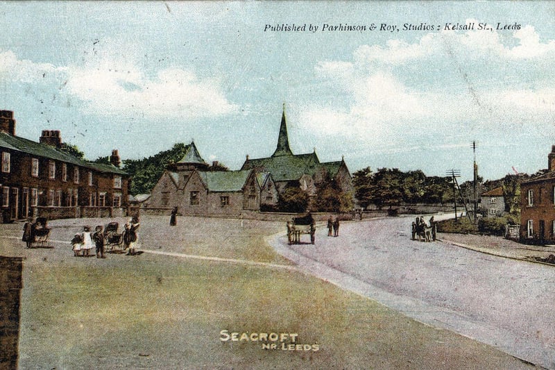 A colour tinted postcard of Seacroft with a postmark of August 24, 1904. The view looks along Town Street, as York Road was known at the time, towards the National School and St. James's Church in the centre. Backhouse Yard is to the left and Marshall's grocery store on the right. Several people, including children, can be seen as well as horses and carts.