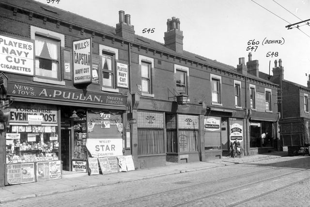 Shops along Compton Road in September 1935. To left is A Pullan, newsagents, with clear view of shop windows and contents. Next is Ramsden, dental surgeon, Becks bakery and J Coldwell furniture removals. A boy on a bike is standing outside Becks and a furniture van is parked outside Coldwells.