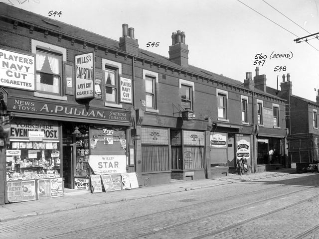 Shops along Compton Road in September 1935. To left is A Pullan, newsagents, with clear view of shop windows and contents. Next is Ramsden, dental surgeon, Becks bakery and J Coldwell furniture removals. A boy on a bike is standing outside Becks and a furniture van is parked outside Coldwells.