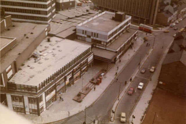 An aerial view looking down on the roof tops of the Merrion Centre with Merrion Street on the right. Rising above the Merrion Centre on the left is the office block Wade House, while the tall building towards the top right is Fairfax House on Wade Lane.