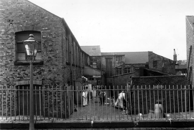 This yard, seen from Little Town Lane, was to the rear of 121 Elland Road. The front of the building indicates two businesses, Northan Chairworks and Waterhouse's sweets and toffee works. Crates and containers are stacked in the yard, a number of workmen can be seen. Pictured in September 1960.