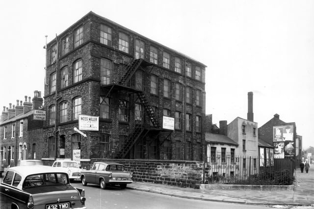 This is the corner of Benson Street and Sheepscar Street South in October 1962. Benson Street is on the left, the large factory building was number 19. Used for tailoring and sewing, it has been constructed with the maximun number of windows to give the best light. In this view it is occupied by Davies Richardson Tailors Ltd and Moss Miller, general warehousemen. Next on the right are the premises of L. Rosenbloom and Sons, joiners. Their address was 2 Vulcan Street. Sheepscar Beck is running past these buildings, set down the banking beyond the railings following the line of Sheepscar Street South.