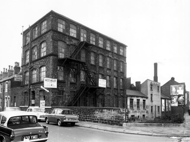 This is the corner of Benson Street and Sheepscar Street South in October 1962. Benson Street is on the left, the large factory building was number 19. Used for tailoring and sewing, it has been constructed with the maximun number of windows to give the best light. In this view it is occupied by Davies Richardson Tailors Ltd and Moss Miller, general warehousemen. Next on the right are the premises of L. Rosenbloom and Sons, joiners. Their address was 2 Vulcan Street. Sheepscar Beck is running past these buildings, set down the banking beyond the railings following the line of Sheepscar Street South.