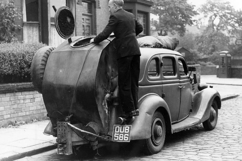 'Performance was poor and you finished the ride smelling of kippers.' A man loads the furnace of his gas powered car in June 1951.