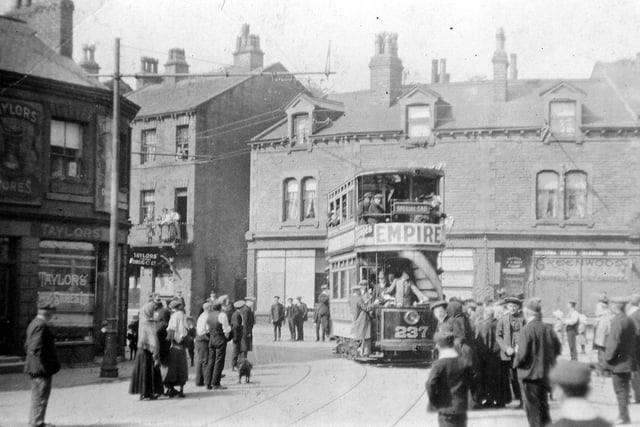 This photo was taken three days before the official opening of the first section of the Morley tram route which took place on July 5, 1911. It shows the Traffic Manager, Mr. J.B. Hamilton, putting tramcar number 237 through its paces during the test run on July 2, 1911. The area is called Morley Bottoms and is the at the end of Queen Street where the junctions of Scatcherd Hill, Chapel Hill, Brunswick Street and Station Road converge. Crowds of people are lining the streets for a preview, some standing on a balcony and leaning from an upper storey window in Queen Street.