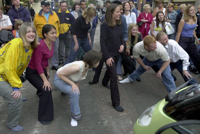 Members of the public pictured limbering up before attempting to break the world record - for fitting as many people as they can into a Smart car parked in Briggate, Leeds city centre. The record stood at 15, which was not broken on that day, but matched.