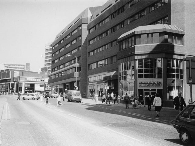 Albion Street showing St. John's Shopping Centre which opened in 1985. The Leamington Spa Building Society and National Provincial Building Society are among businesses occupying premises around the outside. On the left, past the junction with Merrion Street, is the Merrion Centre on Woodhouse Lane.