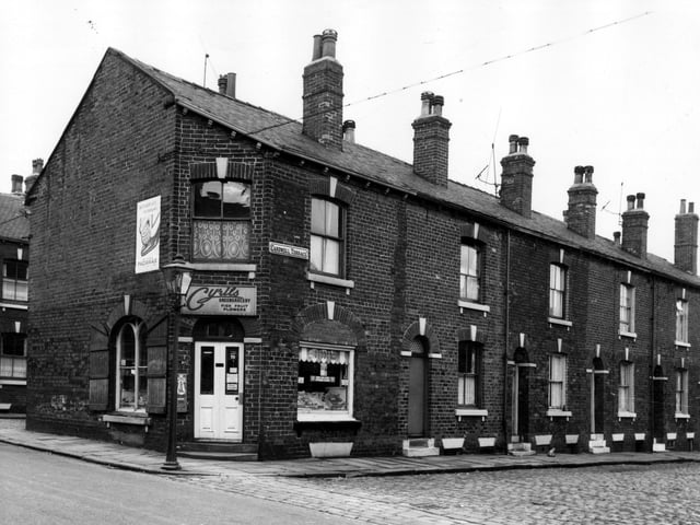 On the left of this view is Cyril's greengrocery, which also sells fish, fruit and flowers. This was number 10 Main Road. Cardwell Street runs to the right edge, numbers 3 to 9 are in view. These houses awaited demolition in line with the citywide slum clearance programme.
