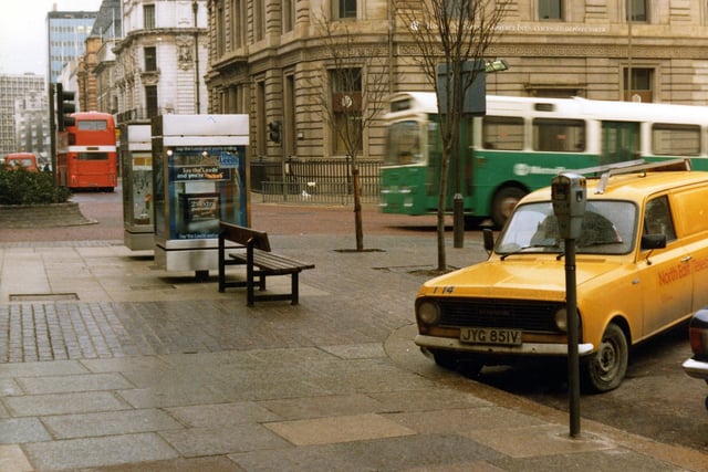 The Headrow seen from the junction with Cookridge Street. Park Row is on the left. Two advertising display boxes can be seen in the centre. A van is parked in the foreground and two buses are visible. Pictured in November 1980.
