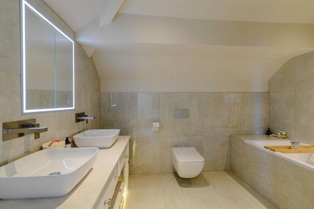 Side by side wash basins, set within a sizeable vanity unit form part of the suite within this plush bathroom.