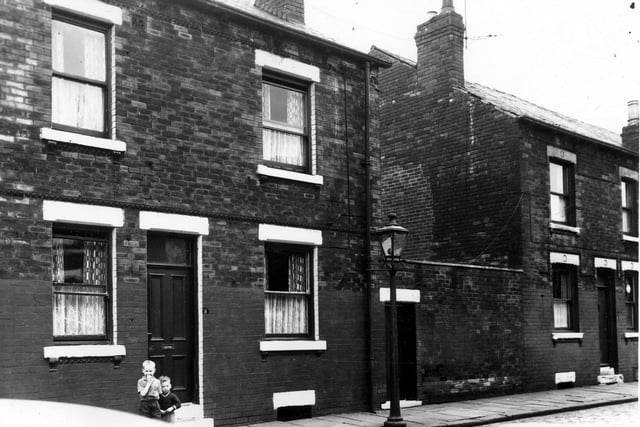 Two back-to-back terraced house separated by a yard originally built to house the shared outside toilet. On the left two small boys stand outside no.3. This area was soon to be demolished and families relocated as part of a Leeds City Council slum clearance programme. Pictured in August 1963.