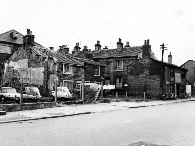 Fowler's Buildings on Town Street in August 1963. On the far right is the T.H. Wortley cycle shop where cycles are lined up on the pavement outside. On the left of the image cars are parked in a wire fenced in plot of land. Two of the cars are Heinkel bubble cars. These were a popular form of transport in 1960s as the tiny car was taxed as a motorcycle and cheap to run.