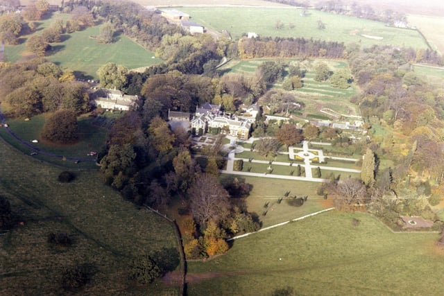 An aerial view of Lotherton Hall taken in 1979 from the Skyview Aerial Archive. The Hall is visible in the centre with its formal gardens. Behind Lotherton Hall to the right the Bird Garden is under construction. The construction workers were a group of 16 year-olds taking part in a joint employment scheme run by Leeds City Council's Department of Leisure Services and the Manpower Services Commission. The Bird Garden opened in April 1980 on the site of the old kitchen gardens belonging to the Gascoigne family of Lotherton Hall. After the initial success of the new venture, the scheme was resumed and new additions to the Bird Garden opened in 1983. The aviaries were constructed from reclaimed timber. Nowadays, over 200 species of bird, many rare and endangered, can be viewed by the public. The buildings left of the Hall were former dwellings, stables and motor car garages. In 1985 the Stable Cafe opened there and there is also the Estate gift shop.