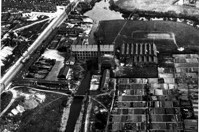A bird's eye view of Burley Mills on Kirkstall Road in September 1950. In the foreground on the right are allotments. Burley Mills was built over a cutting giving access to the river. The River Aire can be seen to the right of the industrial complex. On far side of Kirkstall Road are terraced houses and newly built houses.
