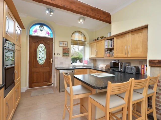 A large open plan breakfast kitchen and family room is fitted with a range of matching wall and base units including a breakfast bar.